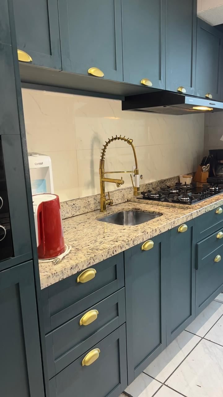 Detalhe da bancada de granito com torneira dourada, cuba e cooktop