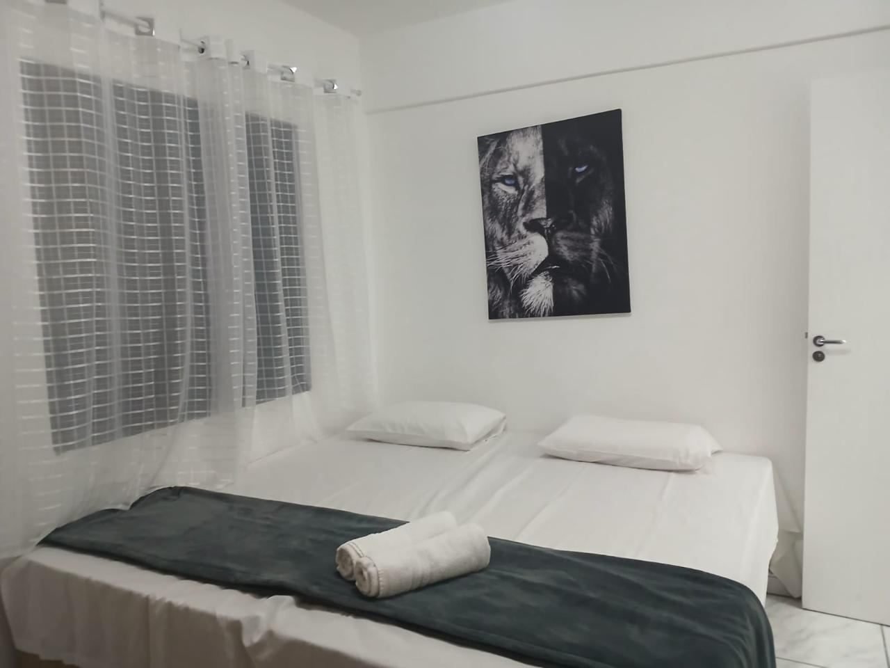 Quarto claro com duas camas de solteiro unidas e quadro na parede