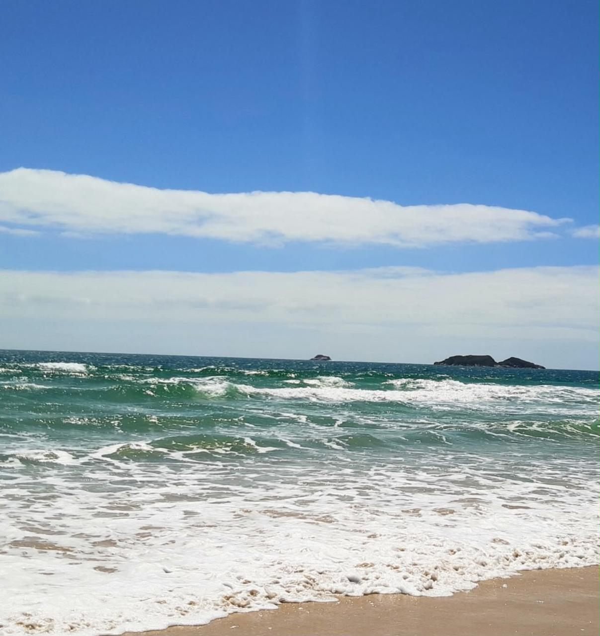 Ondas quebrando na areia da praia dos Ingleses, com as ilhas ao fundo