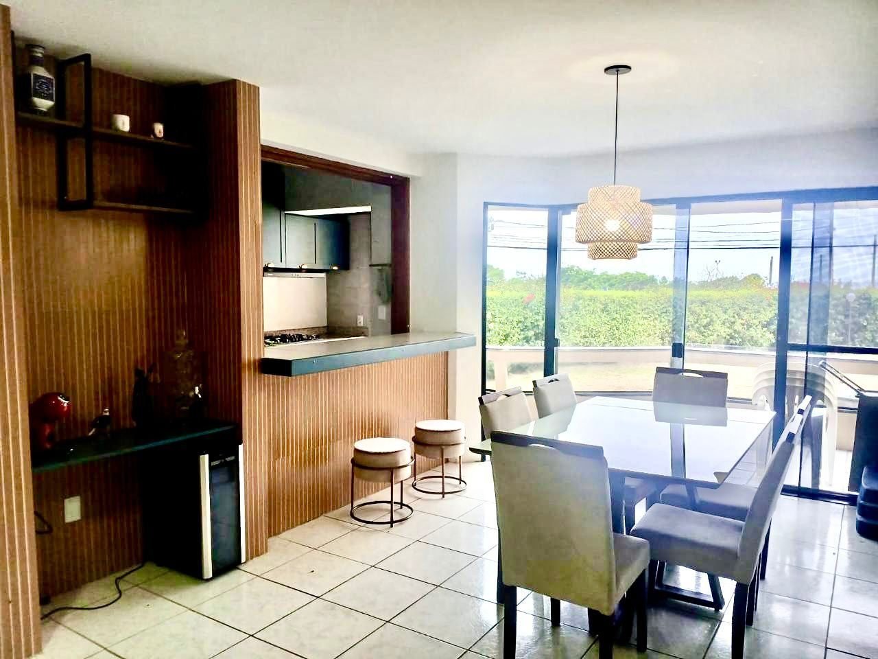 Sala de jantar com mesa de vidro para seis lugares e luminária pendente de palha