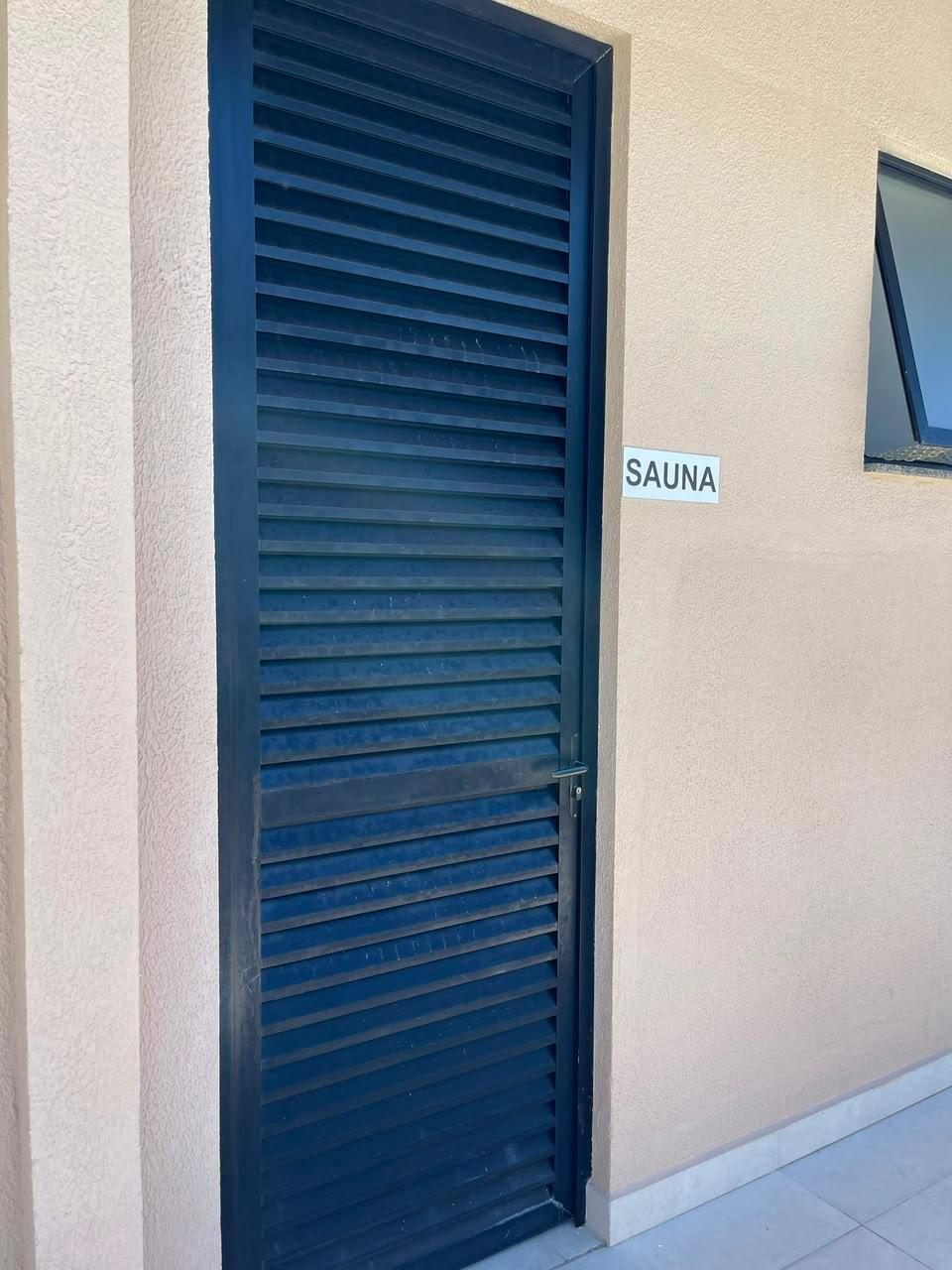 Porta da sauna do condomínio, com placa de identificação